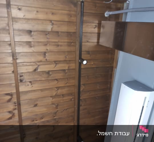 מזגן מותקן על קיר עץ עם צינור חשמל